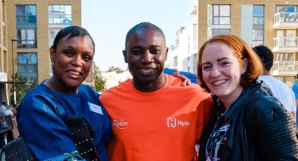 Three Hyde staff members in a street, a woman in traditional African dress, a man in a sporty Hyde t-shirt and a woman in business clothes.