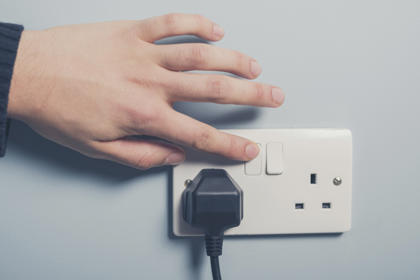 Male hand pressing a power switch on the wall