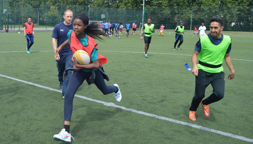 Girl sprinting, playing tag rugby in a mixed community event.
